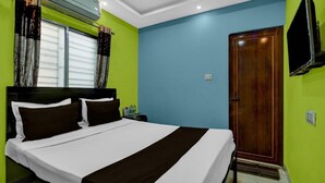 A hotel room with a large bed, a wooden door, and a mounted TV. - Hotel O Metropolis Mall Kolkata (Barasat)