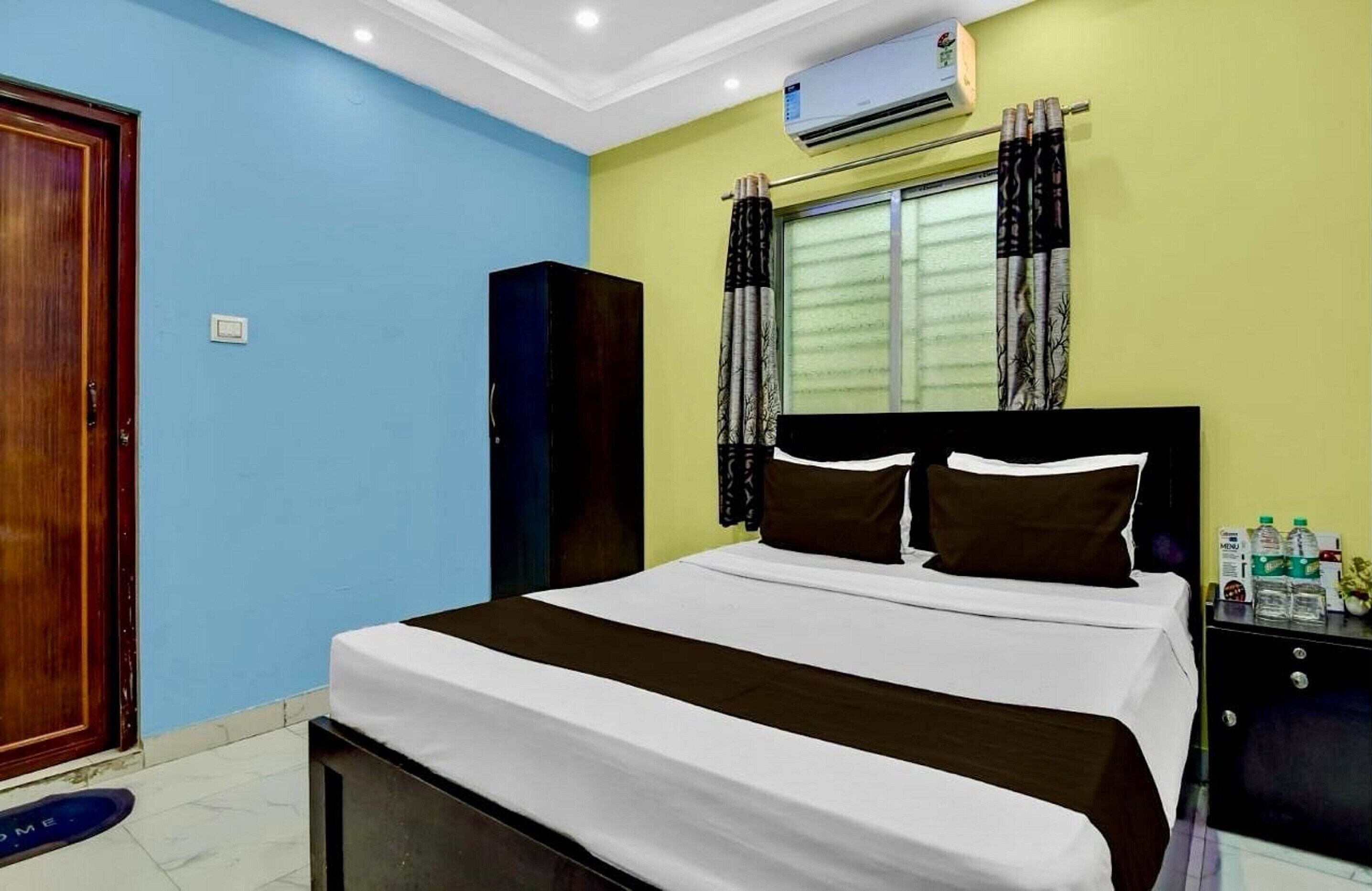 A bedroom with a bed, a wardrobe, a nightstand, and an air conditioning unit.