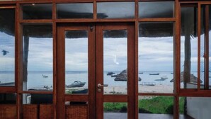 Eine Holztür mit Glasschildern, die auf einen Strand blickt.