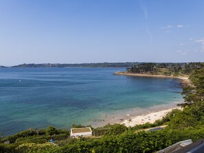 A coastal view with a beach, clear water, and a distant shoreline with buildings.