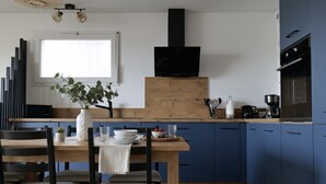 Una cocina moderna con armarios azules, una mesa de comedor de madera y una campana extractora negra.