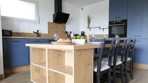 Una cocina moderna con armarios azules, una isla de madera y una zona de comedor con sillas.