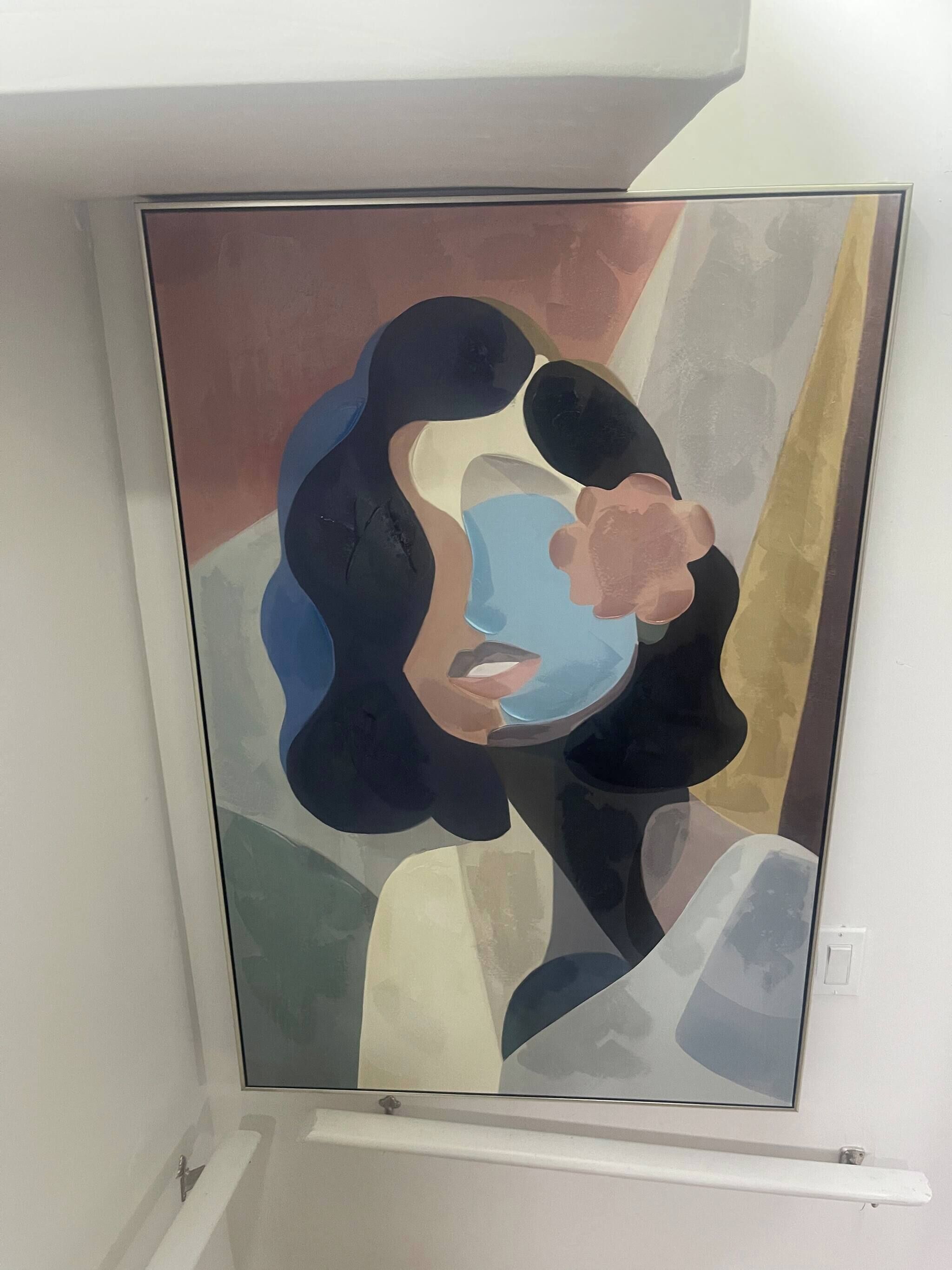 A framed abstract painting on a white wall.