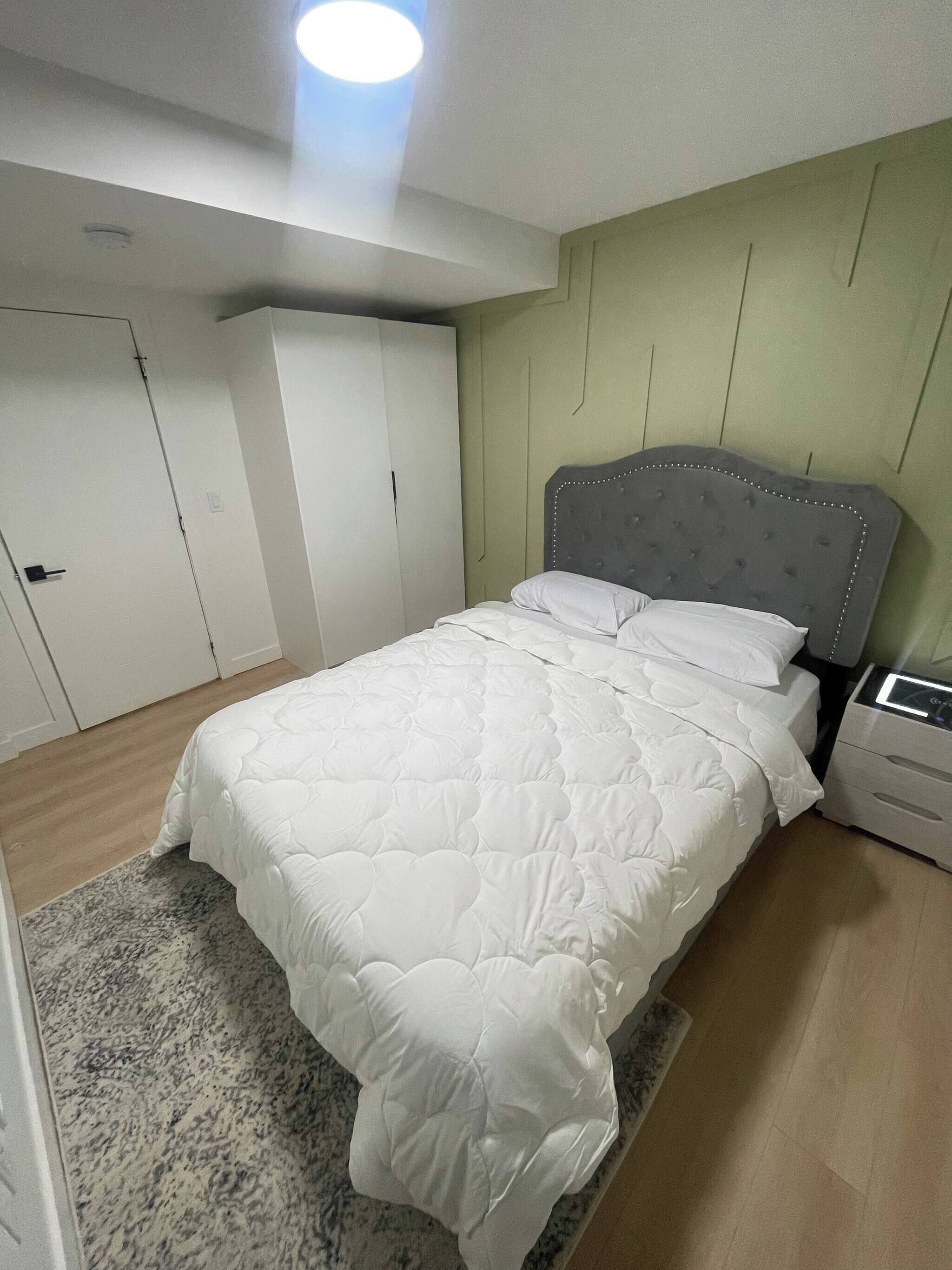 Une chambre à coucher avec un lit, une table de chevet, une armoire et une porte.