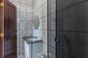 Un baño con puerta de madera, un lavabo con espejo y zona de ducha.
