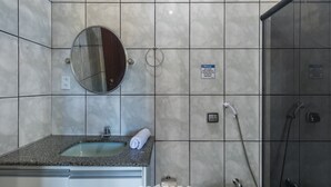 Un bagno con lavabo su piano in granito, uno specchio rotondo, un asciugamano, una doccia con soffione manuale e un cartello che indica un bagno privato.