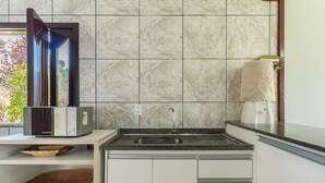 A kitchen with a marble backsplash, a built-in oven, a sink, and a window with a view of greenery. - Apt w/ Balcony 600m From the Beach Qda0001 (Santa Cruz Cabralia)