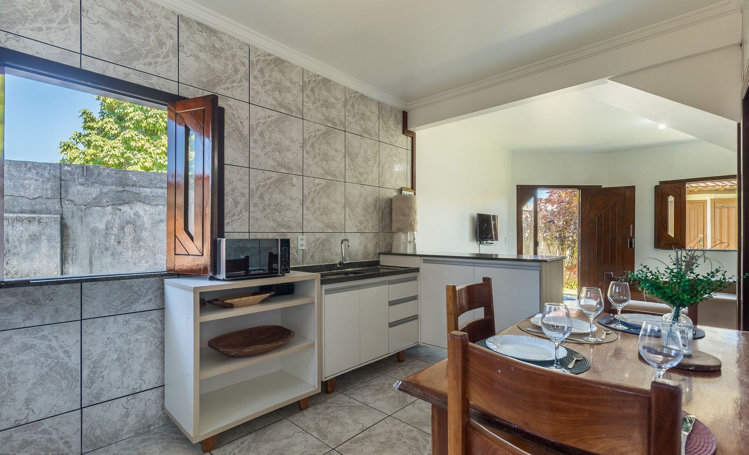 A modern kitchen with a built-in microwave, a sink, and a dining area with a table set for two.