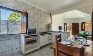 Una cocina moderna con microondas incorporado, un lavamanos y un comedor con una mesa dispuesta para dos.