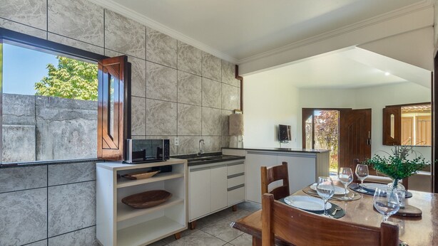 A modern kitchen with a built-in microwave, a sink, and a dining area with a table set for two. - Apt w/ Balcony 600m From the Beach Qda0001 (Santa Cruz Cabralia)