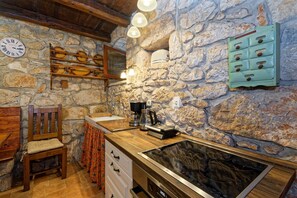 Eine rustikale Küche mit Steinwand, Holzmöbeln, einem eingebauten Herd und einer Uhr.