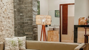 Un soggiorno moderno con una parete decorata in pietra, un divano beige, un tavolino in legno e una lampada da terra.