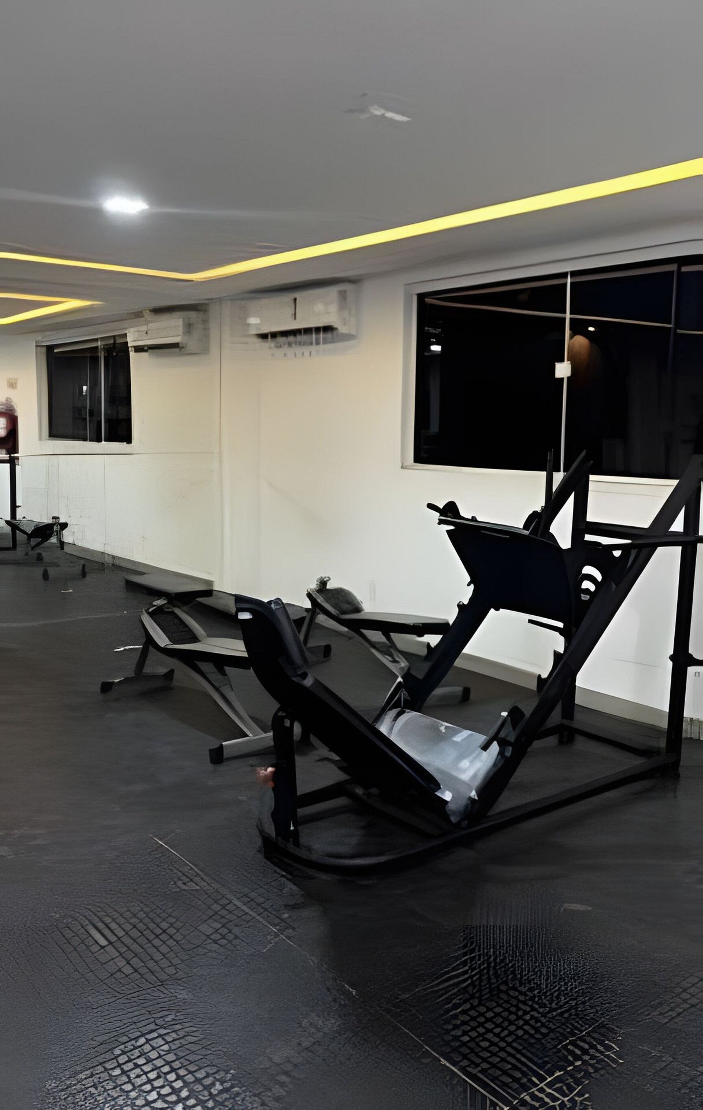 A gym with exercise equipment, a window, and an air conditioning unit.