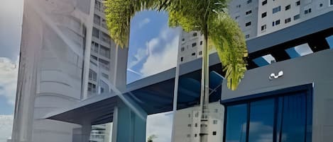 Un edificio moderno con un diseño arquitectónico único, que combina elementos de vidrio y hormigón, rodeado de abundante vegetación.
