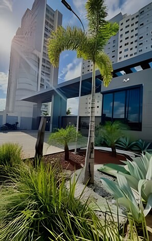 A modern building with a unique architectural design, featuring a mix of glass and concrete elements, and surrounded by lush greenery. - 1505 Lazer conforto e tranquilidade (Cabedelo)