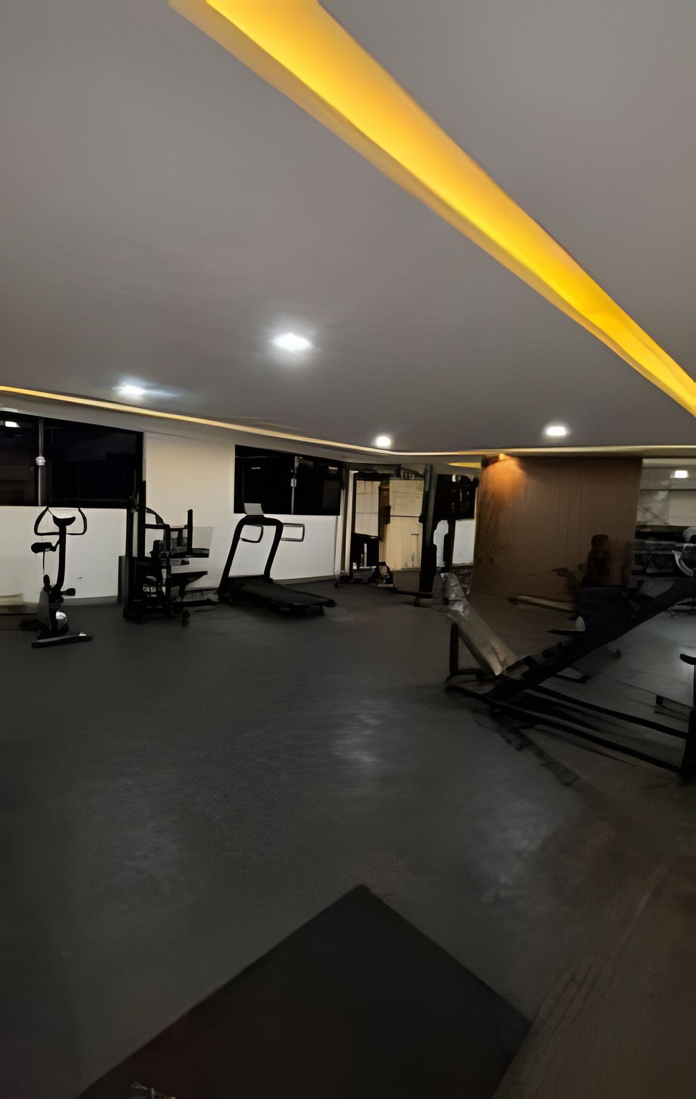 Un gimnasio con equipo de ejercicio, cinta de correr y un televisor montado en la pared.