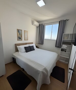 Une chambre d’hôtel comprenant un lit, un bureau, une chaise, une fenêtre avec des rideaux et des œuvres d’art accrochées au mur.