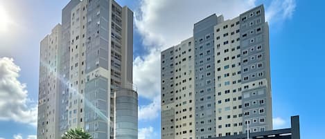 A modern high-rise building with a cylindrical structure, multiple floors, and a covered entrance area.