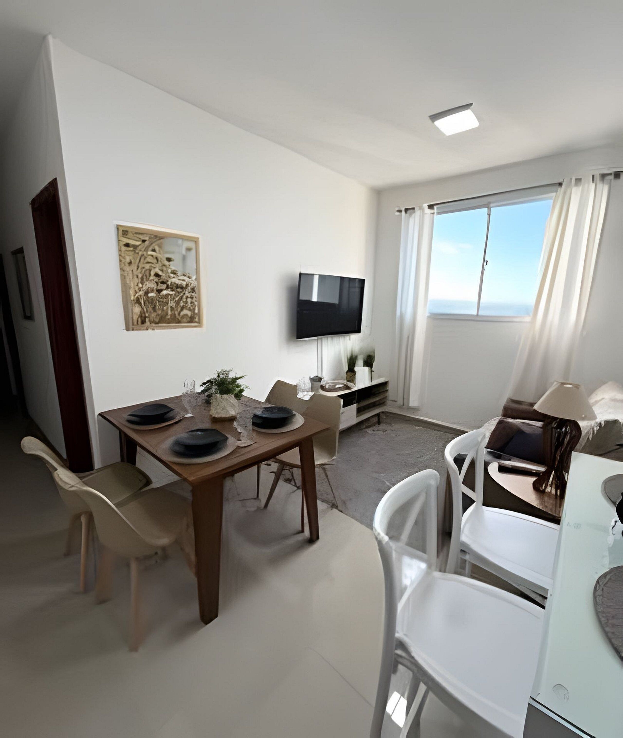 A modern living room with a dining area, a flat-screen TV mounted on the wall, and a large window with curtains.