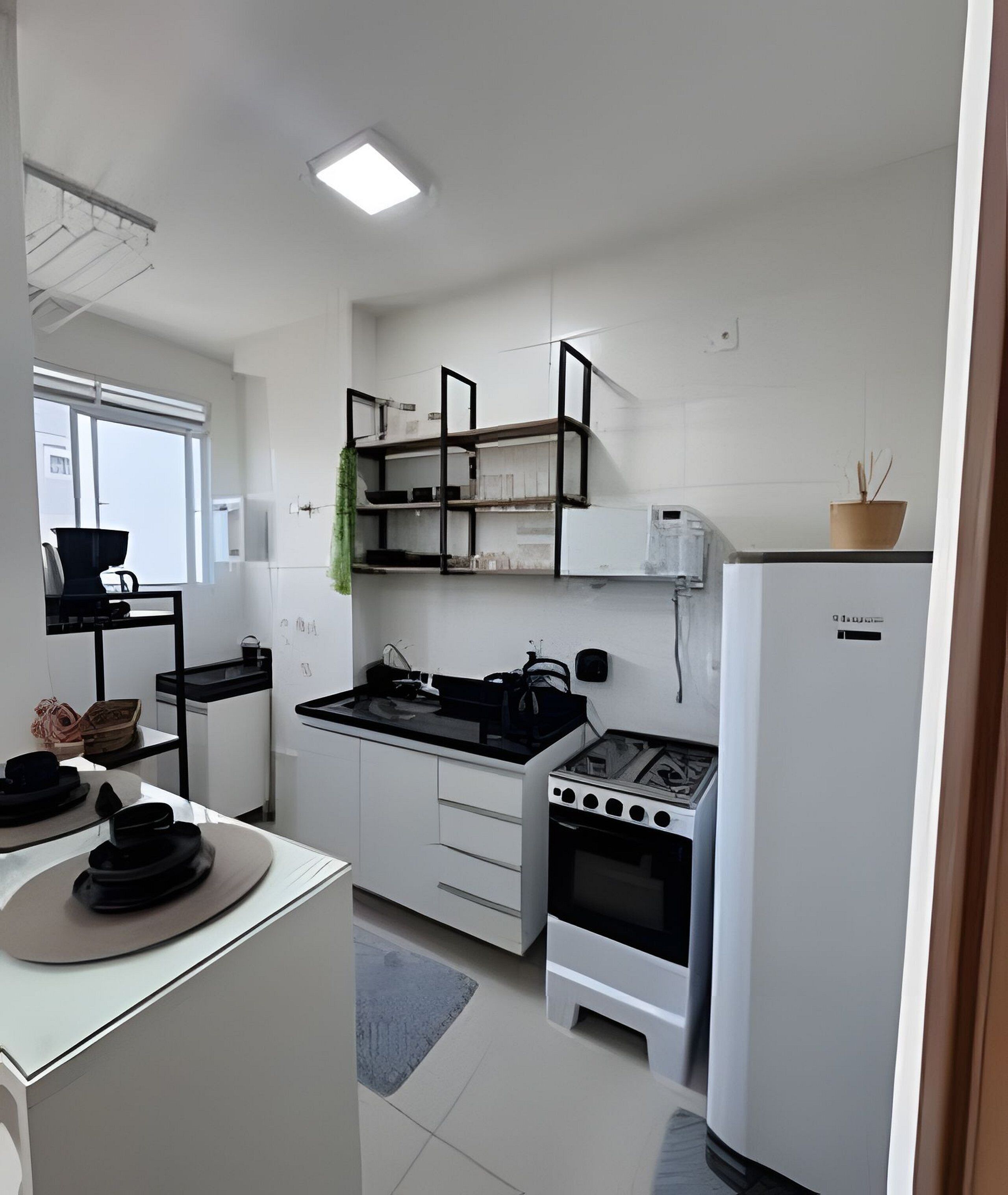 Eine kleine Küche mit weißen Schränken, einem Gasherd, einem Backofen und einem Kühlschrank.