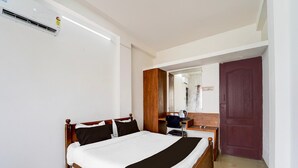 Ein Hotelzimmer mit Bett, Schreibtisch mit Stuhl, Spiegel und Tür.