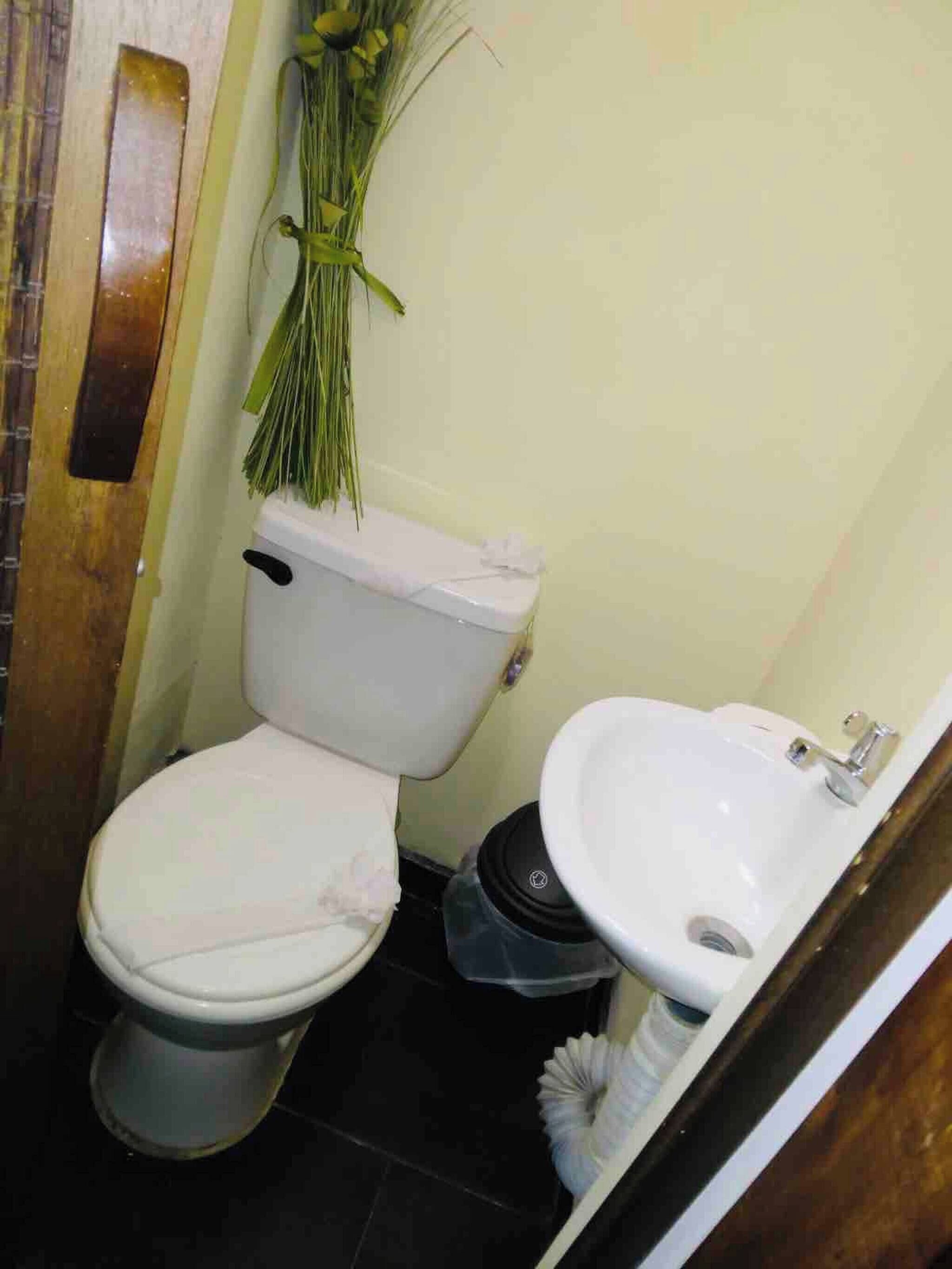 A small bathroom with a toilet, bidet, and a trash bin.