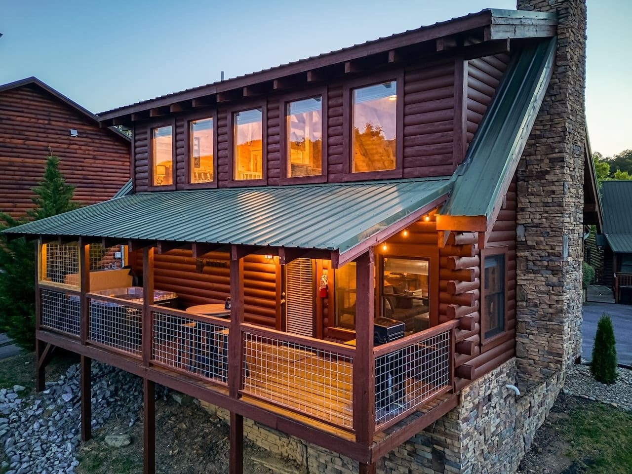 A log cabin with a balcony, a stone chimney, and a metal awning.