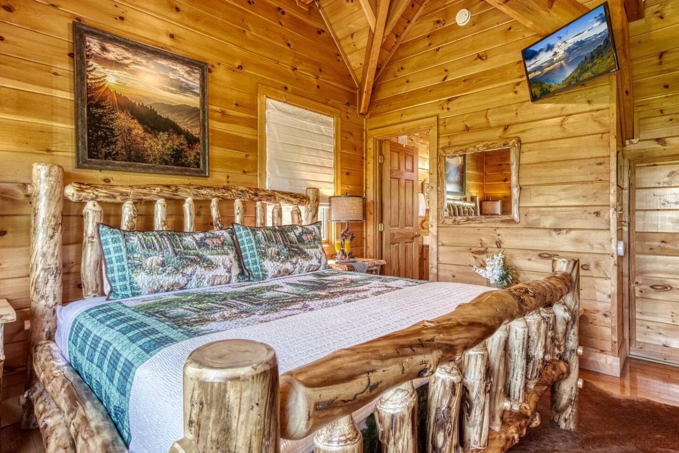 A log cabin room with a bed, wooden headboard, and a painting of a forest landscape.