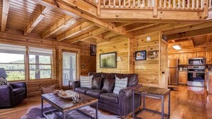 A wooden cabin interior with a living room, kitchen, and large windows. - New Listing Alert: Hot Tub, Views, Fireplace (Pigeon Forge)