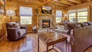 A log cabin interior with a fireplace, leather furniture, and wooden floors. - New Listing Alert: Hot Tub, Views, Fireplace (Pigeon Forge)