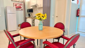 A dining area with a round wooden table, red upholstered chairs, and a vase with yellow flowers. - Oshun Estudio Deluxe D312 (Madrid)
