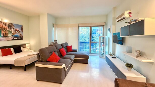 A modern living room with a sofa set, a flat-screen TV, and a balcony with a view. - Oshun Estudio Deluxe D312 (Madrid)