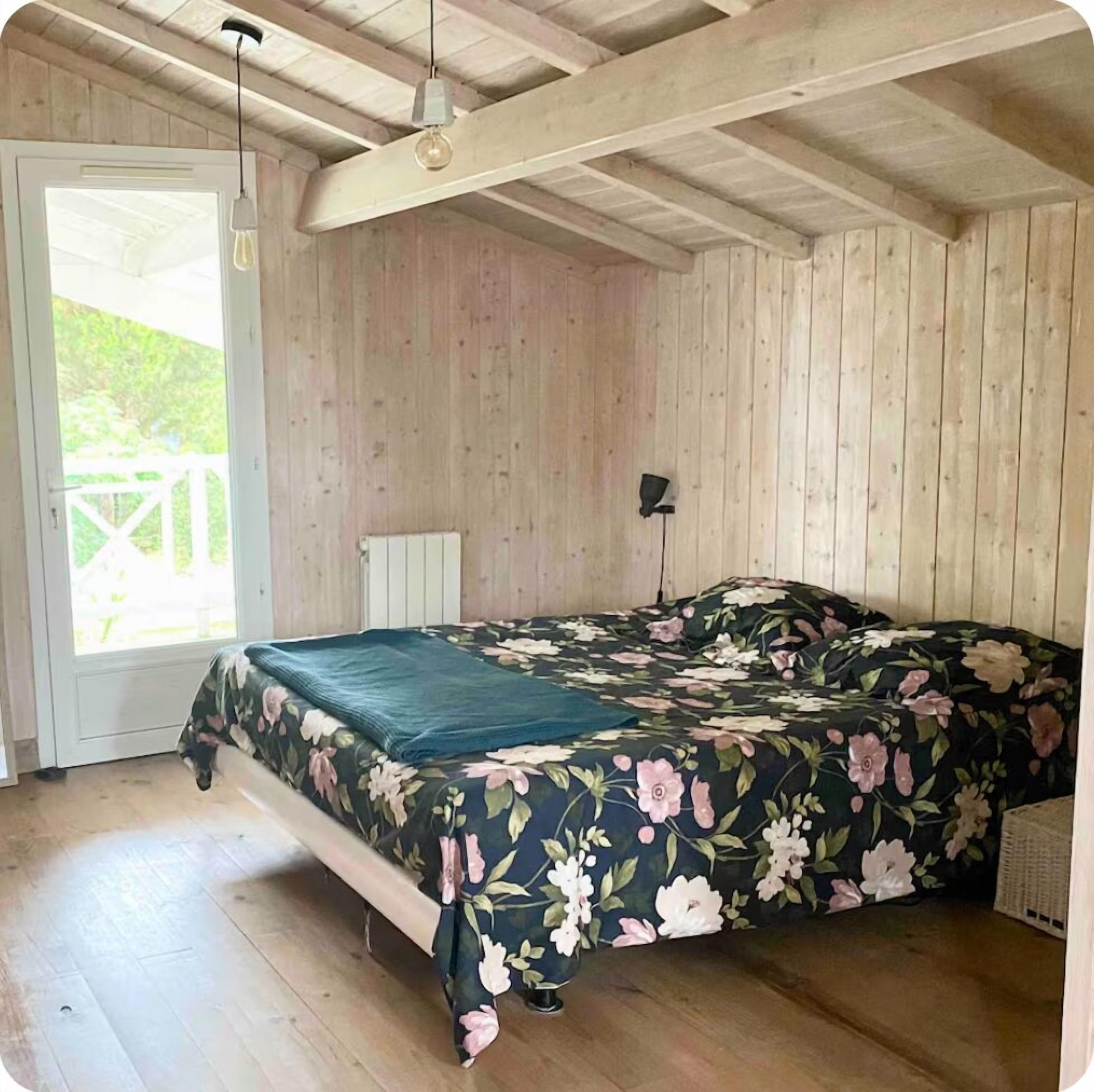 A room with a bed, wooden walls, a door, and a window.