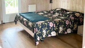 A room with a bed, wooden walls, a door, and a window. - Private air-conditioned villa with heated pool 2nd line Bassin d'Arcachon (Gujan-Mestras)