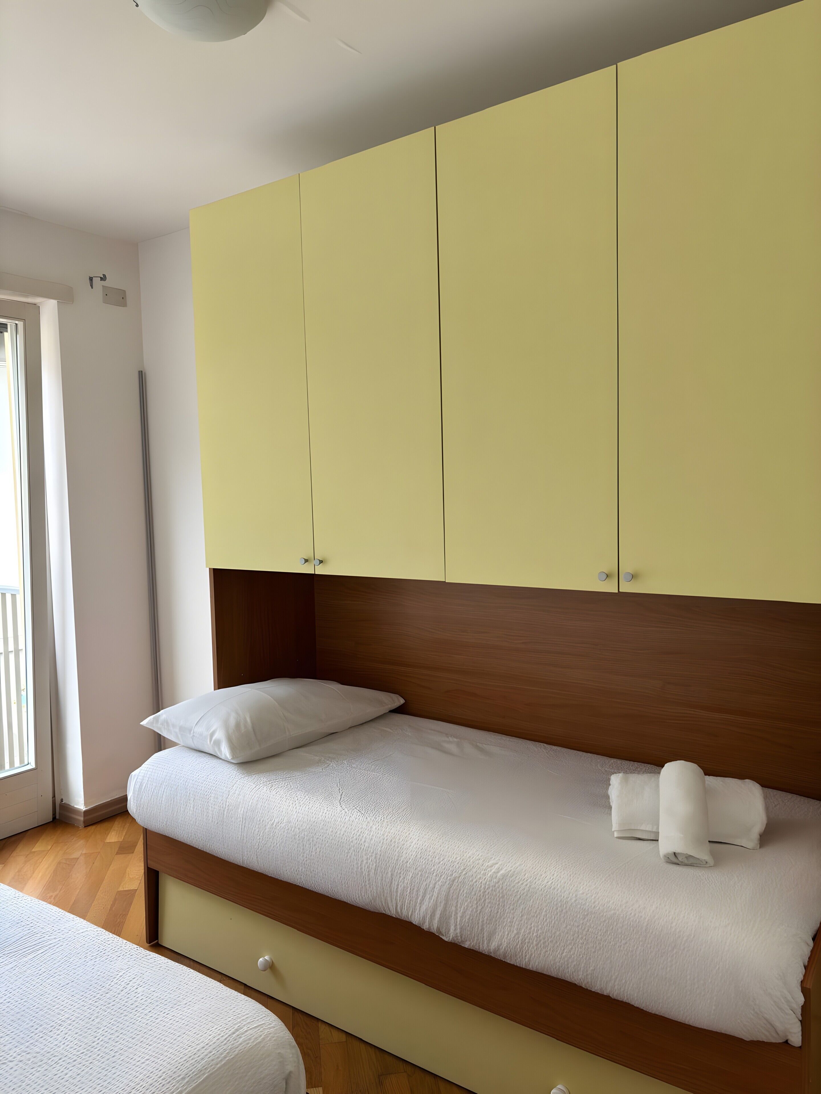 Un dormitorio con cama, cabecera de madera y armarios amarillos.