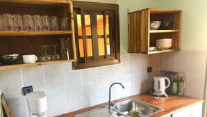 Eine Küche mit Spüle, Kaffeemaschine und einem Fenster mit Jalousien.