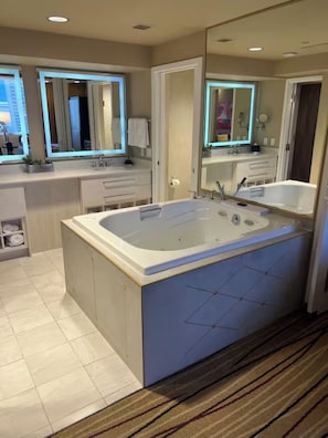 A modern bathroom with a large bathtub, a vanity with a mirror, and a toilet.