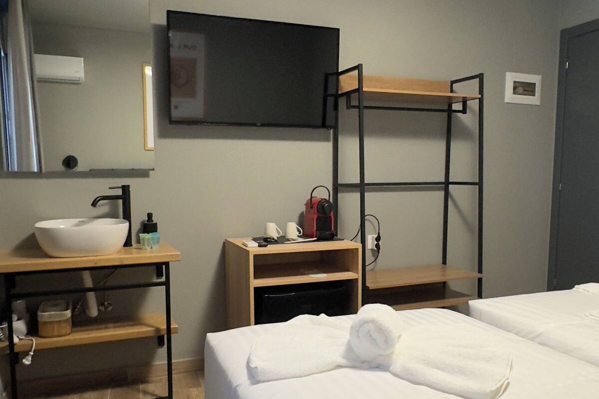 Une chambre d’hôtel avec un lit, une table de chevet avec un lavabo, un miroir et un lit superposé.