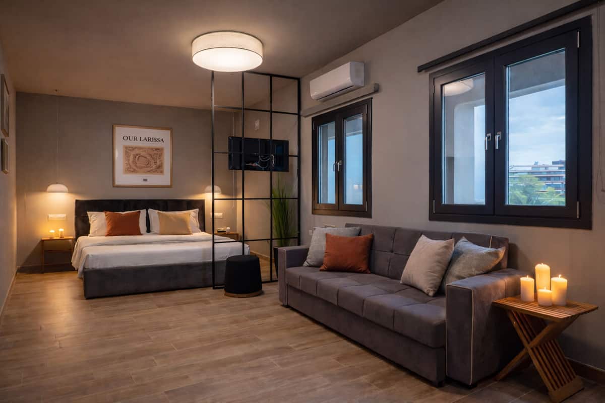 Une chambre moderne avec un lit, un canapé, une télévision et une fenêtre donnant sur la ville.