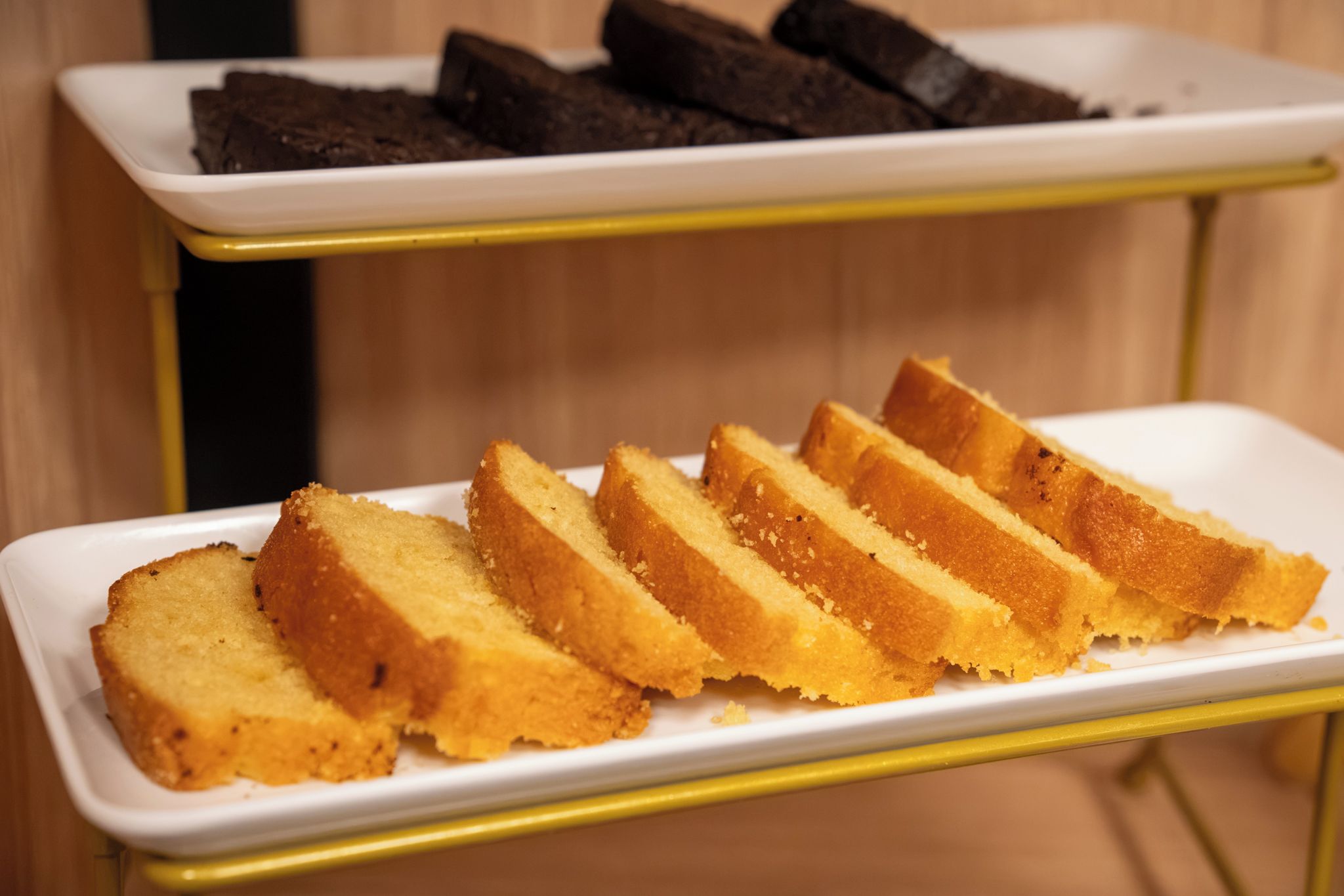 Une assiette rectangulaire blanche sur laquelle sont disposées des tranches de pain, le tout posé sur un présentoir métallique jaune.