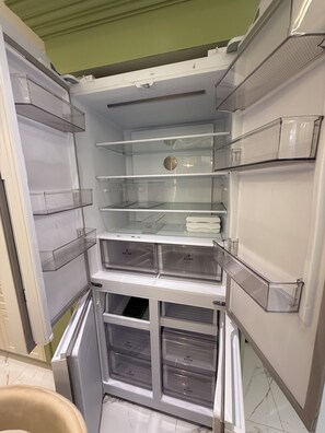 An open refrigerator with multiple transparent storage drawers and shelves. - Azure Resort 2BR Deluxe Beach & Pool View with Bathtub • 8 Pax • Smart Toilet (Parañaque)