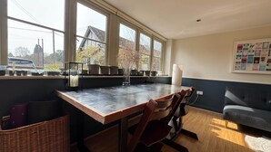 A kitchen with a large window, wooden table, chairs, and a basket.