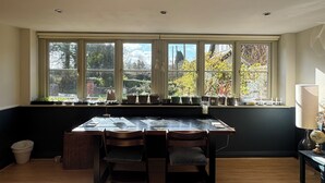 A kitchen with a large window, a dining table, and chairs.