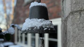 En snötäckt utomhusklocka som är fäst på en byggnadsvägg.