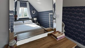 A bedroom with a bed, bedside table, lamp, and a mirror reflecting the room.