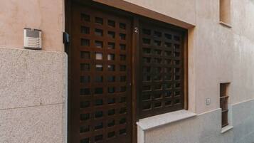 A building facade with a large window featuring a grid of small square openings, a small vent on the left, and a number '2' on the window frame.