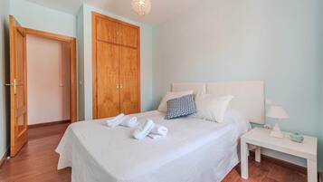 Un dormitorio con una cama, una mesita de noche, un armario de madera y una puerta.