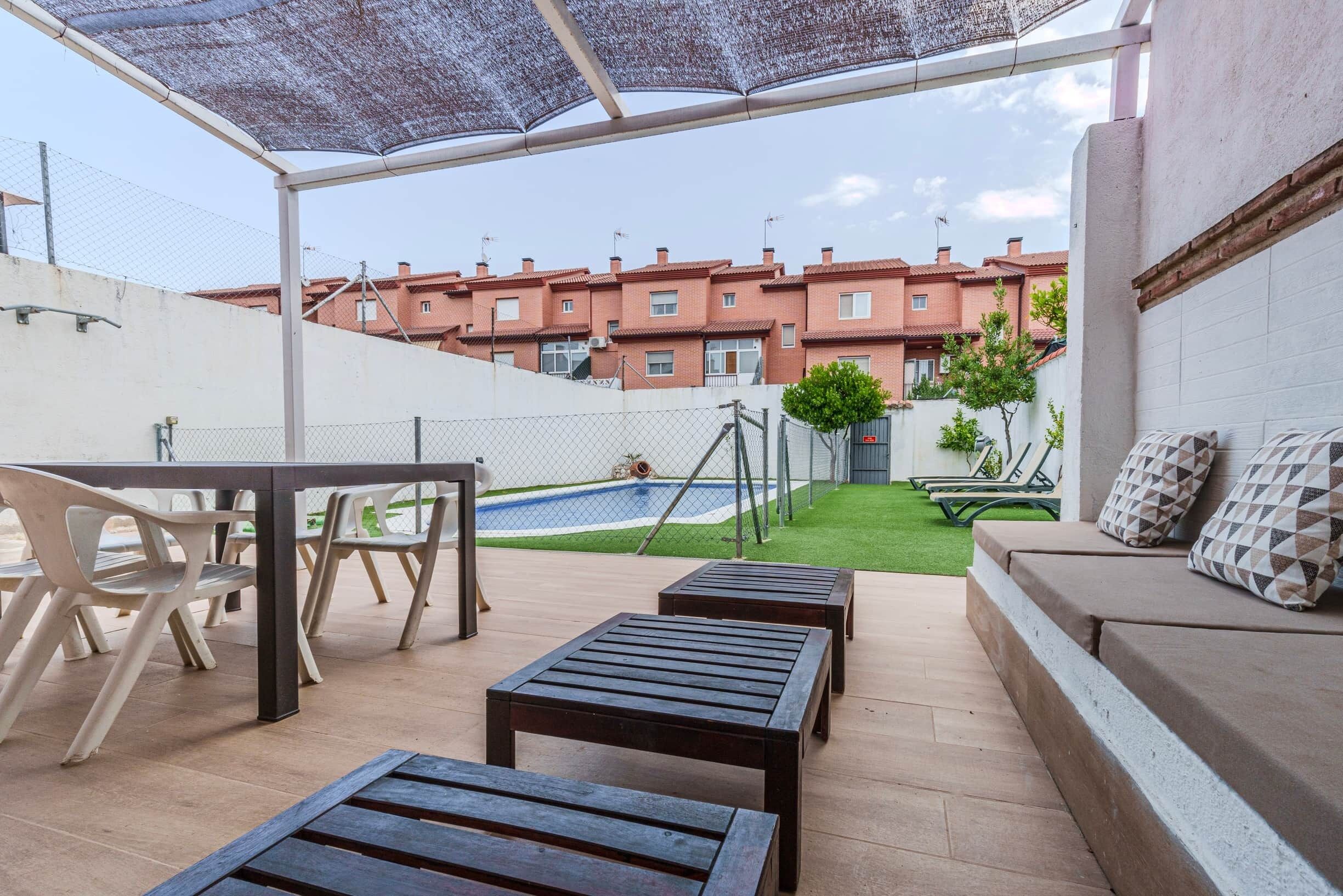 Un patio con mobiliario exterior, una piscina y vistas de un edificio residencial.