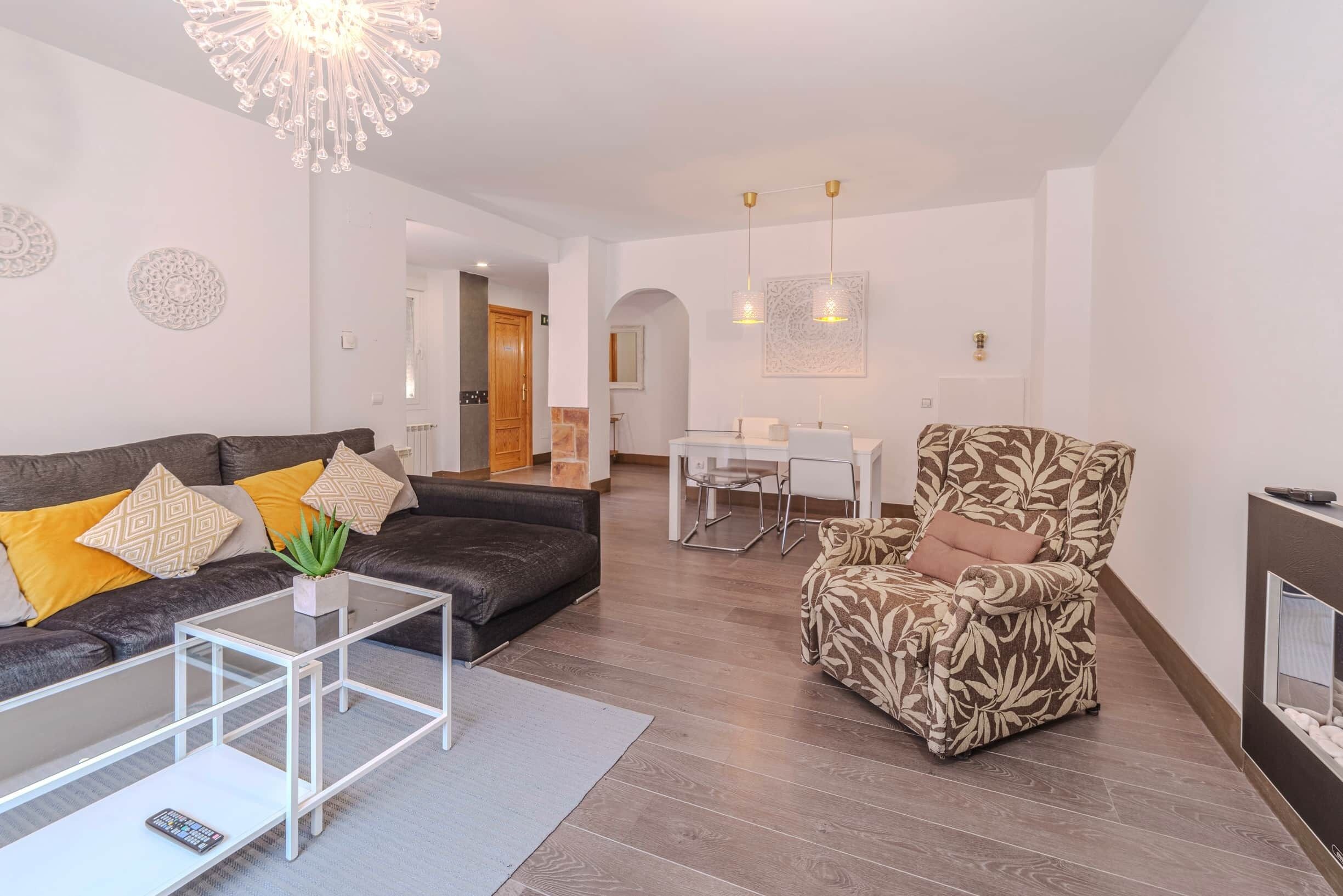 Una sala de estar moderna con sofá, sillón, mesa de centro y comedor.