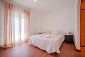 Een slaapkamer met een groot bed, twee nachtkastjes, een houten vloer.